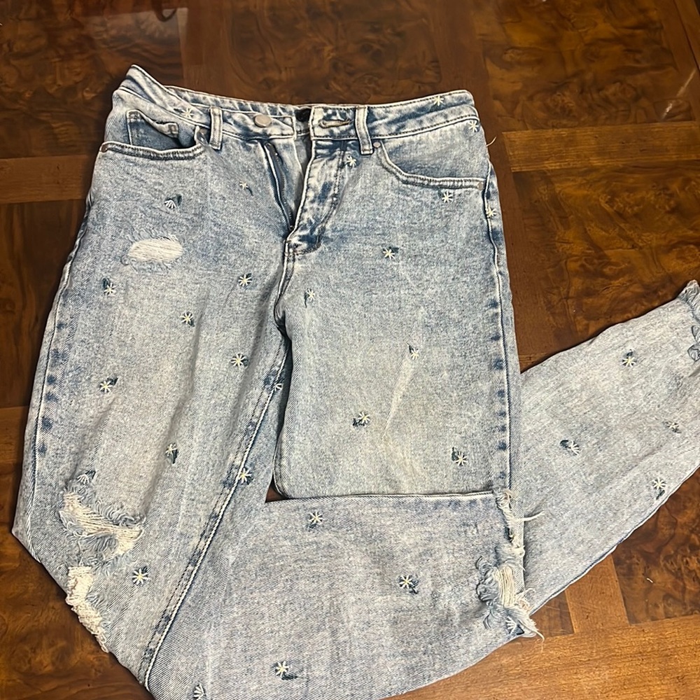 Distressed ripped blue jeans with embroidered daisies
